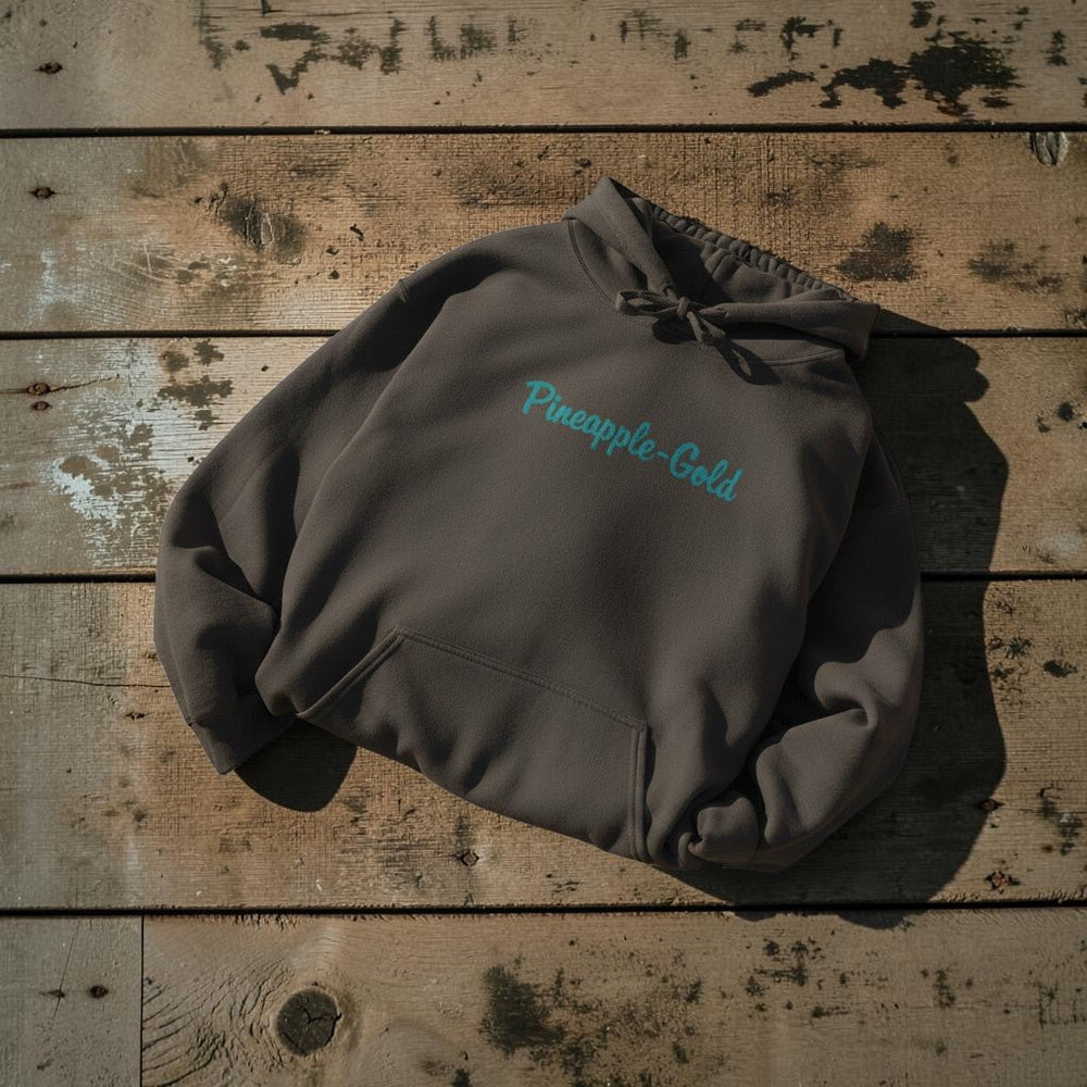 Pineapple-Gold Hoodie in Pepper — front chest graphic, warm sand studio background