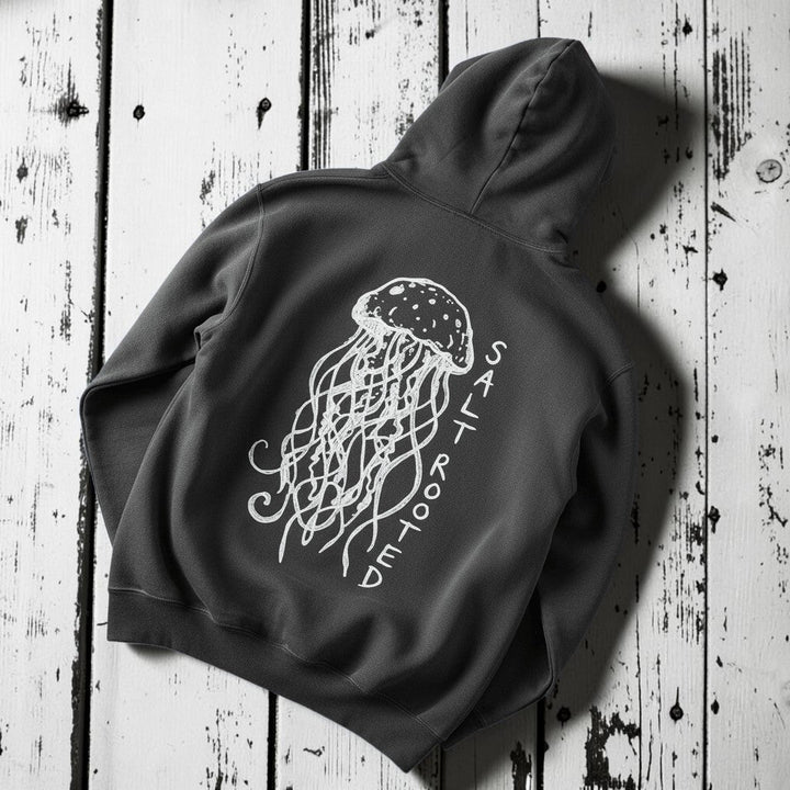 Salt Rooted Jellyfish Hoodie in Pepper Charcoal — back graphic with hand-drawn jellyfish and SALT ROOTED lettering on driftwood