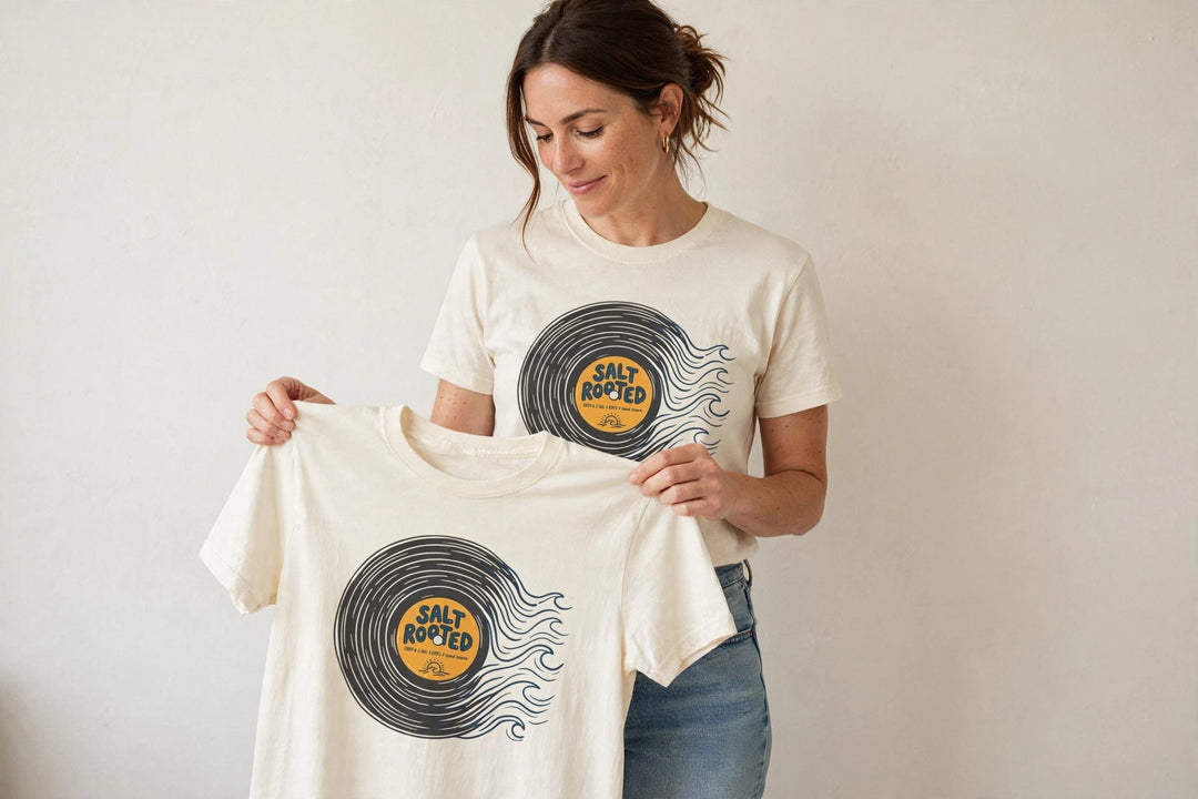 Woman wearing the Salt Rooted Vinyl Record Tee in Ivory, holding up the front print