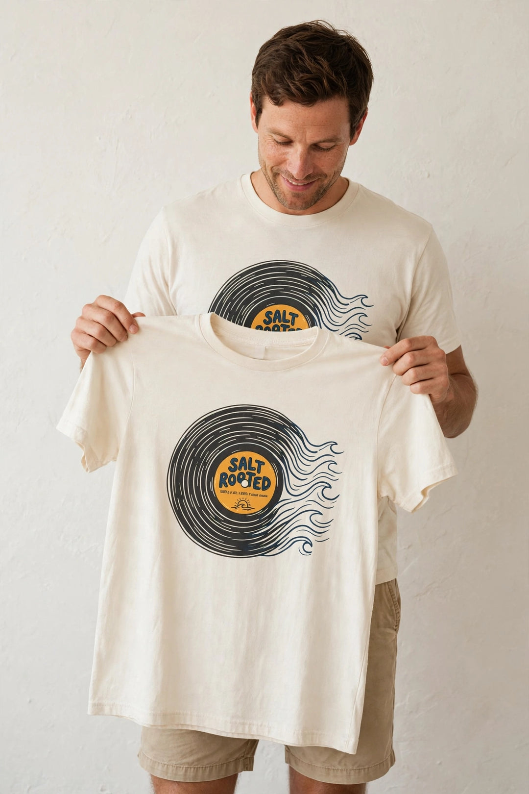 Man wearing the Salt Rooted Vinyl Record Tee in Ivory, holding up the front print