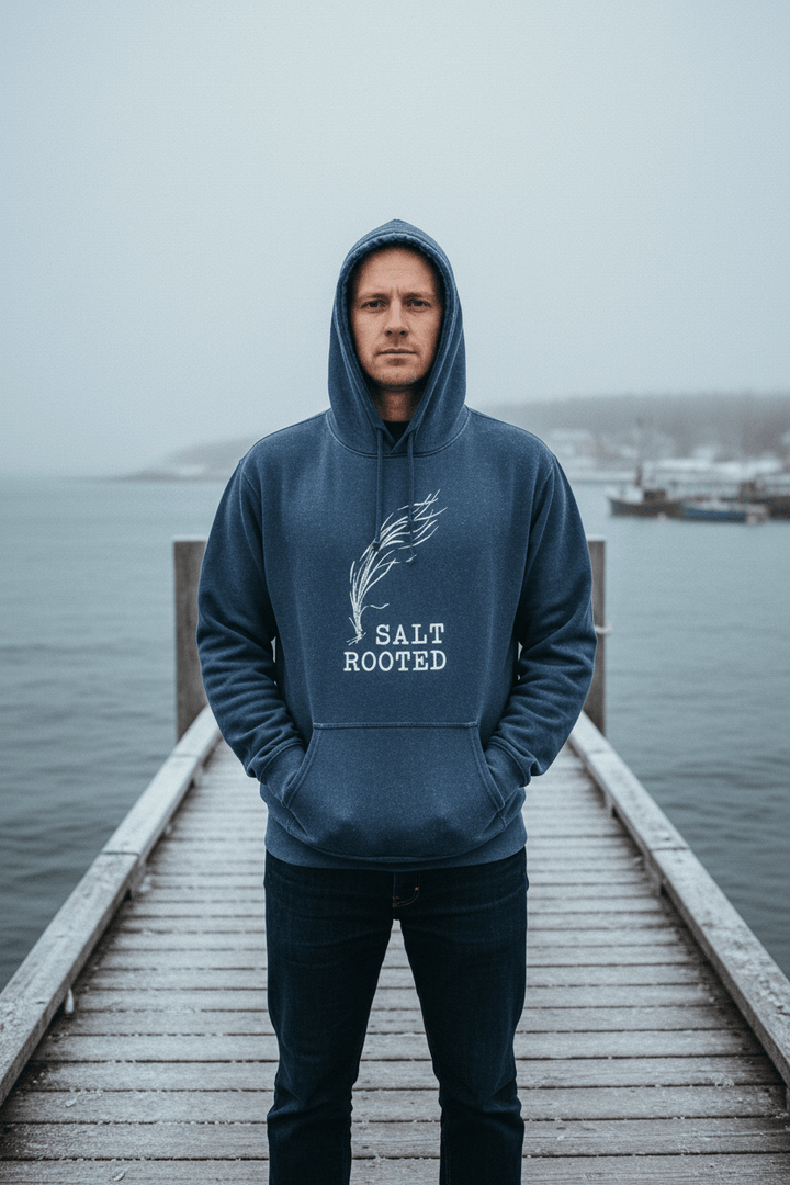 Male model wearing Salt Rooted Wheat Hoodie in Denim on a moody Maine winter coastal dock