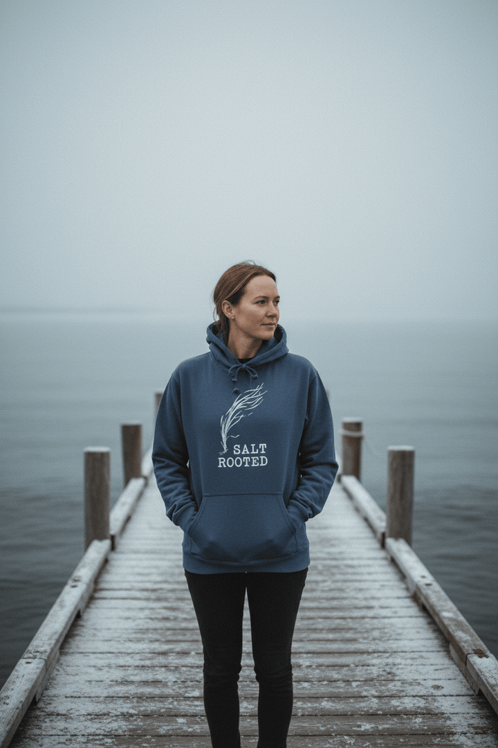 Female model wearing Salt Rooted Wheat Hoodie in Denim on a moody Maine winter coastal dock