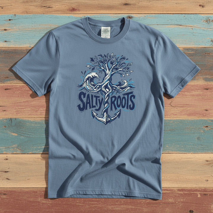 Flat lay - slate blue Salty Roots tee with Comfort Colors label on weathered driftwood planks
