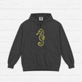 Pepper garment-dyed hoodie front with neon-yellow seahorse chest art, on whitewashed boards.