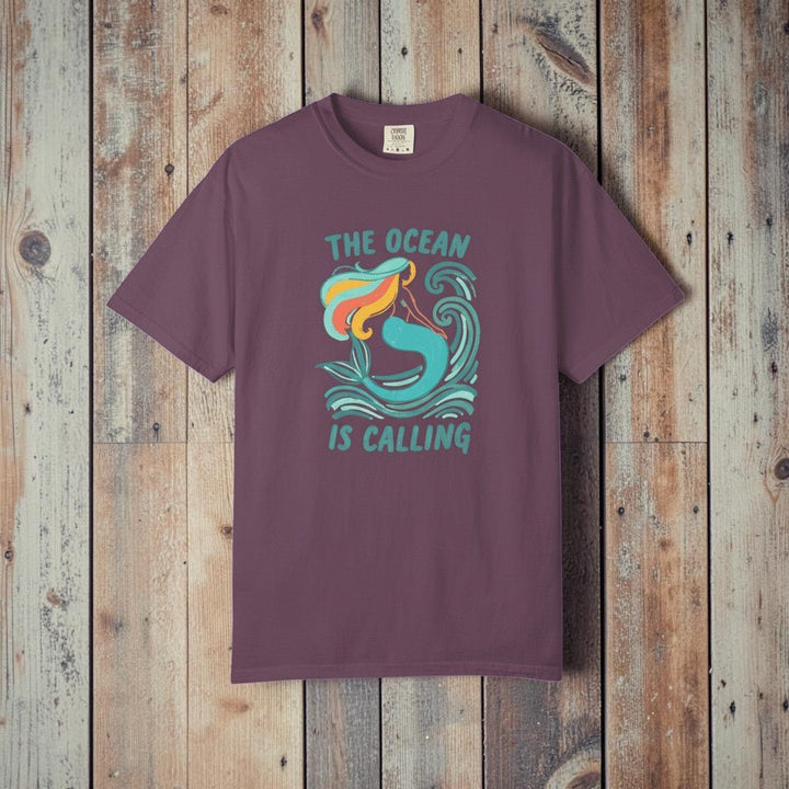 The Ocean Is Calling berry garment-dyed mermaid wave tee laid flat on rustic reclaimed wood