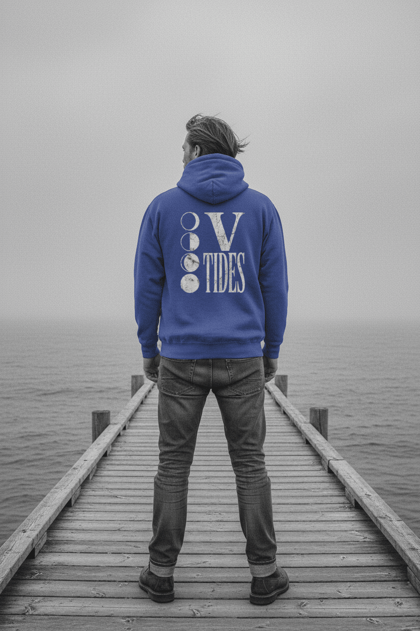 Male model showing back of flo blue V Tides Moon Phases hoodie on grey Maine dock — color pop lifestyle