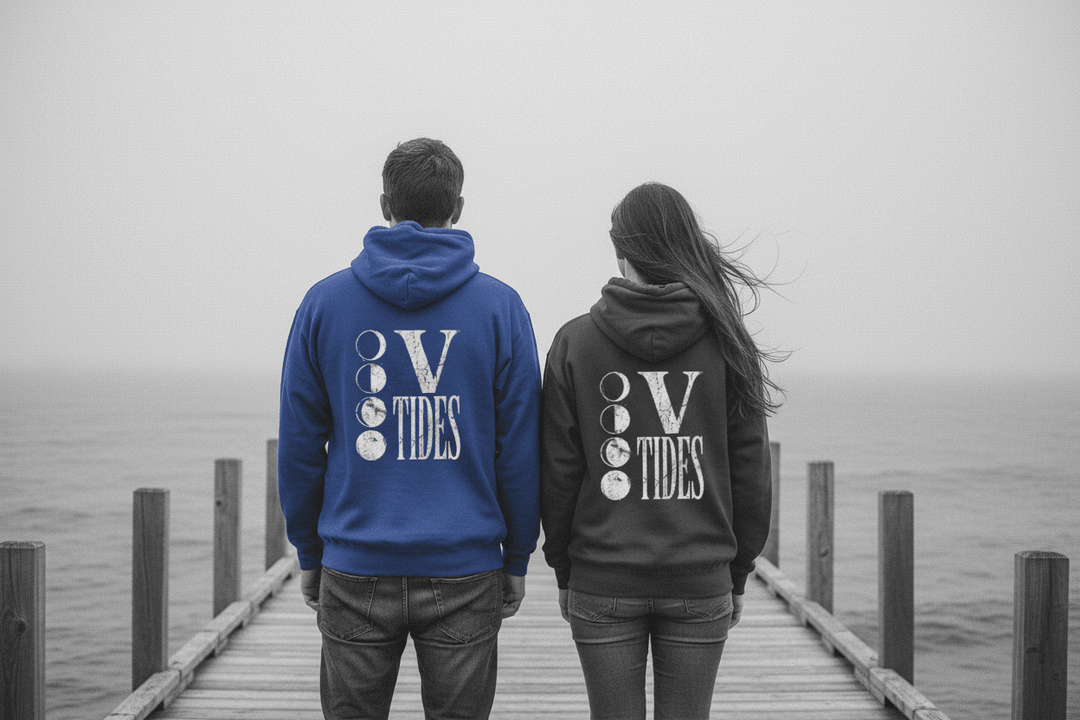 Couple showing backs of flo blue and pepper V Tides Moon Phases hoodies on grey Maine dock — color pop lifestyle