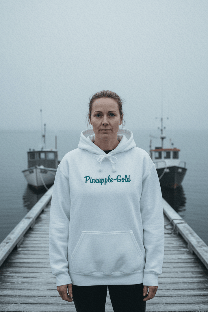 Female model wearing Pineapple-Gold Hoodie in White on a moody Maine winter coastal dock