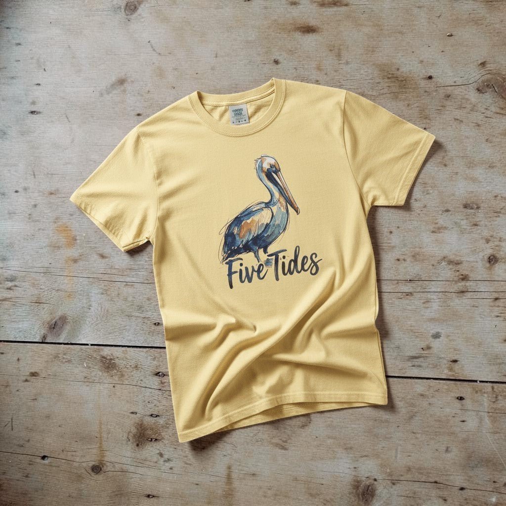 Watercolor Pelican banana garment-dyed tee casually tousled on rustic reclaimed wood